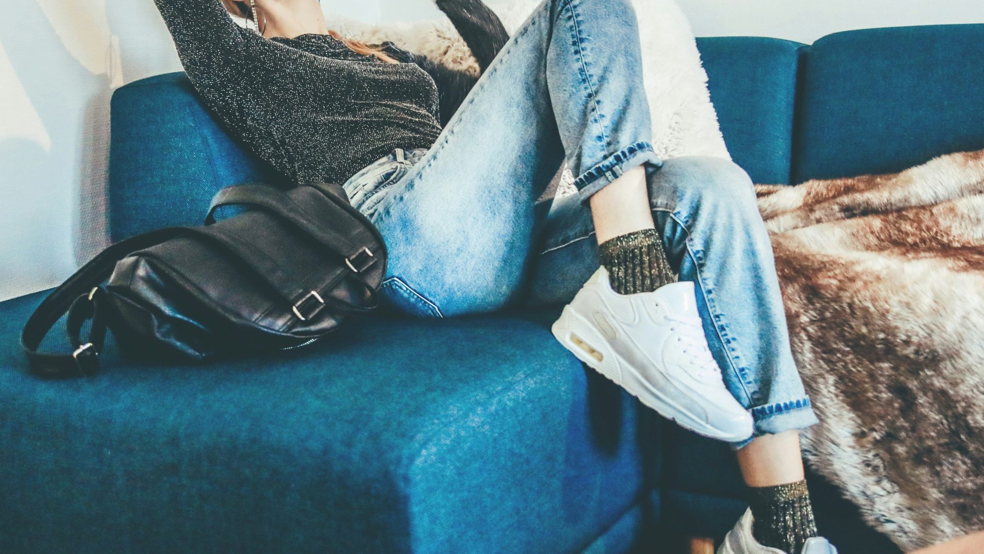 woman sitting on sofa beside bag